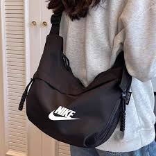حقيبة كتف هلالية الشكل (Crescent Crossbody Bag) تحمل شعار علامة نايكي (Nike).